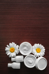 Obraz na płótnie Canvas Cosmetic cream and flower buds on wooden background