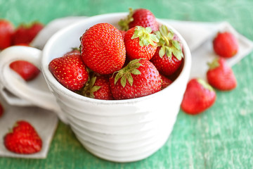 Fresh strawberries in cup on table