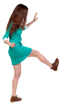 skinny woman funny fights waving his arms and legs. Long-haired brunette in a green dress kicks.