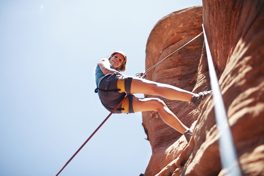 Low angle view of woman climbing mountain against clear sky