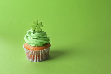 Tasty cupcake with clover on green background. Saint Patrics Day concept