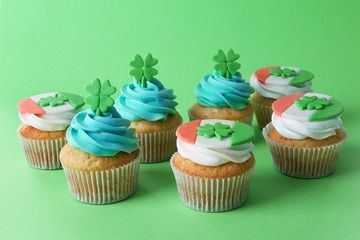 Tasty cupcakes with clover on green background. Saint Patrics Day concept