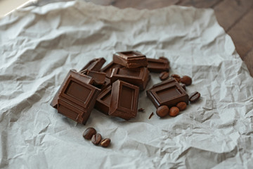 Pile of dark chocolate bars with roasted coffee beans on paper background