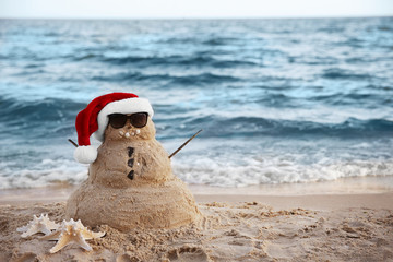 Snowman made of sand on beach. Christmas holiday concept © Africa Studio