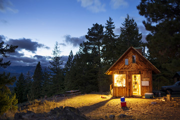 Illuminated wooden cabin in forest at night