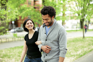 Cheerful multi-ethnic couple walking in park