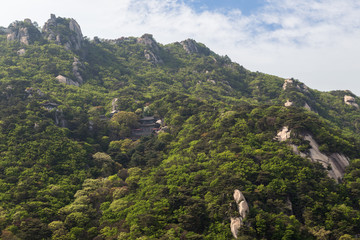View of a temple on steep and lush hillside at the Bukhansan National Park in Seoul, South Korea.