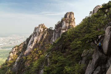 Fototapeta na wymiar Man hiking on a steep cliff at the Jaunbong Peak on Dobongsan Mountain at the Bukhansan National Park in Seoul, South Korea.