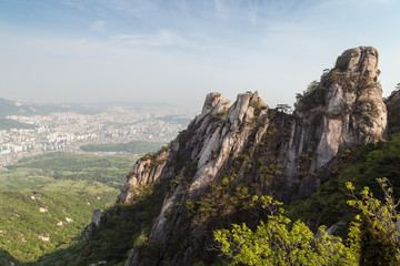 View of the city from above and steep granite peaks of Jaunbong Peak on Dobongsan Mountain at the Bukhansan National Park in Seoul, South Korea.