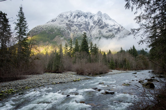 Scenic view of river flowing in forest against snowcapped mountain