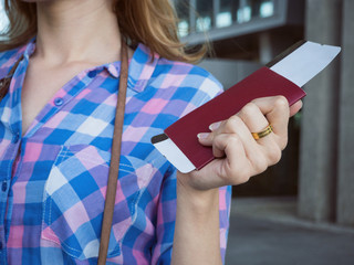 A young girl holds a passport and a plane ticket in his hand. The concept of tourism recreation, vacation and travel.