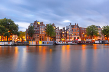 Amsterdam canal Amstel with typical dutch houses and boats during twilight blue hour, Holland,...