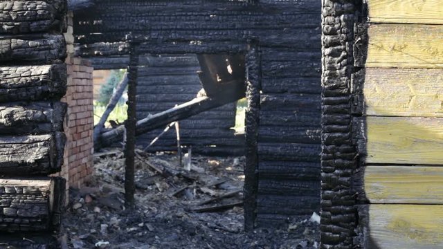 Burned wooden  house, charred logs, daytime, pan
