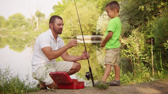 Slow motion father and son setting up a fishing rod