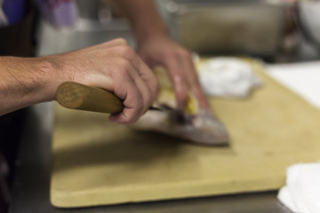 A chef fillets fish before service. 