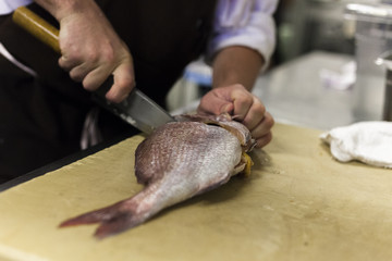 A chef fillets fish before service. 