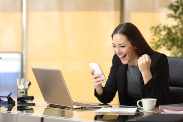 Excited businesswoman reading a smart phone
