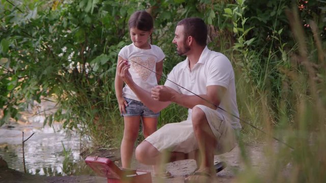 Father teaching daughter how to fish and bait