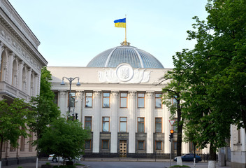 Side view of Ukrainian parliament building. The coat of arms of Ukraine is on the wall. Words above...
