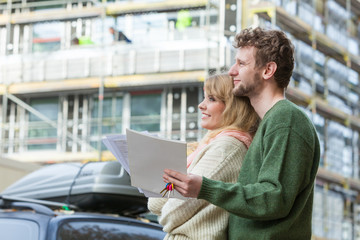 Couple with blueprint project keys on construction site