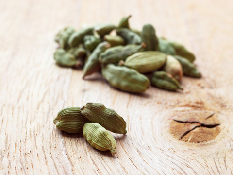 Green cardamom pods on wooden background