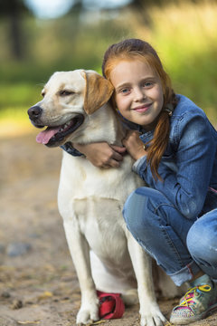 Little cute girl hugs dog (Labrador)