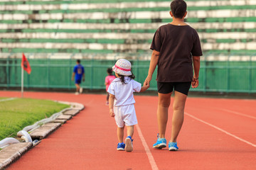 Mother holding her daughter hand and walking in running track