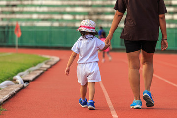 Obraz premium Mother holding her daughter hand and walking in running track