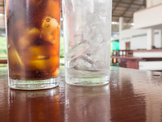 Selective focus surface empty glass with ice and glass of cola.
