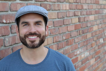 Portrait of handsome bearded man in hat standing , isolated on red brick wall classic background