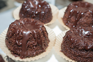 Chocolate muffins with chocolate syrup on dark background, selective focus.