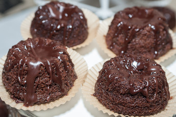 Chocolate muffins with chocolate syrup on dark background, selective focus.