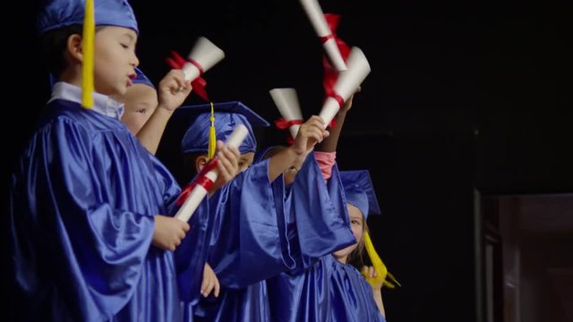 School kids graduating with diplomas