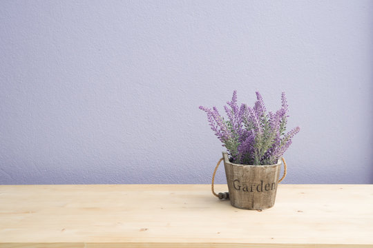 Fototapeta Wood table with purple lavender flower on flower pot and  purple cement wall.