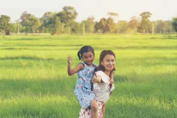 Fototapeta premium Happy Mother and daughter showing thumbs up in the green field.