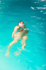 Woman athlete swimming backstroke in pool.