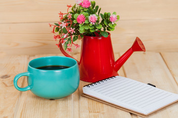 note book with cup and vase on wood table