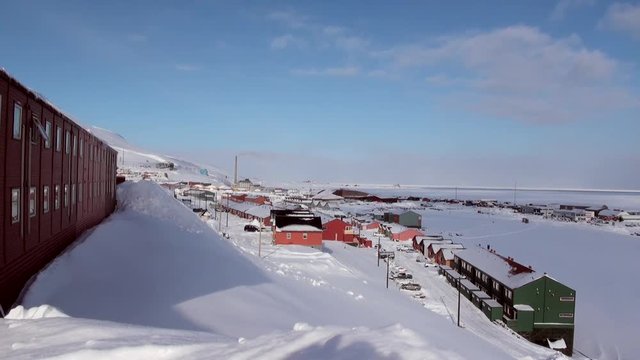 Landscape and buildings, roads in Small town Longyearbyen on shores of Arctic ocean among snow capped mountains of Norwegian Archipelago of Svalbard in early spring in Norway. Sunny day in April.