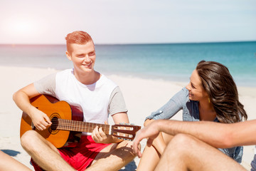 Beautiful young people with guitar on beach