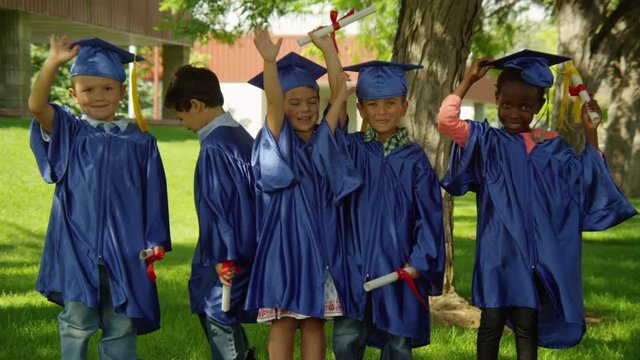Young children graduating and throwing caps
