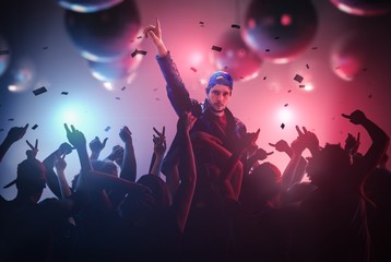 DJ or singer has hand up at disco party in club with crowd of people.