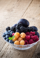 Fresh summer berries and fruits in  glass bowl on wooden rustic