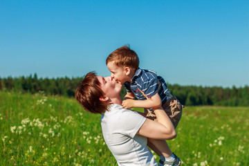 Fototapeta premium Young brunette with short hair playing with his son in the field