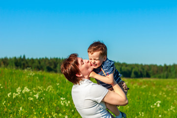 Fototapeta premium Young brunette with short hair playing with his son in the field