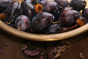 Natural organic plums in copper basin. Rustic style.