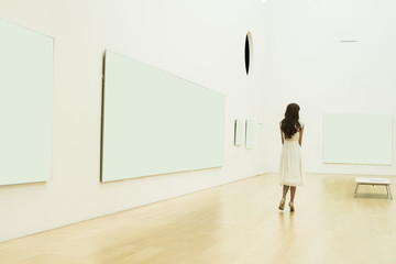 Young woman is looking at the painting in the museum