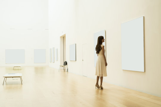 Young woman is looking at the painting in the museum
