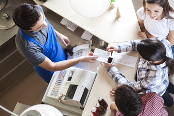 Waiter Giving Receipt To Woman With Family At Icecream Parlor