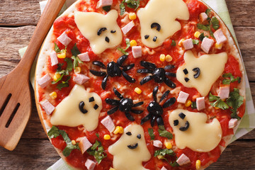 Fototapeta na wymiar pizza for Halloween with ham, cheese and olives close-up. Horizontal top view 