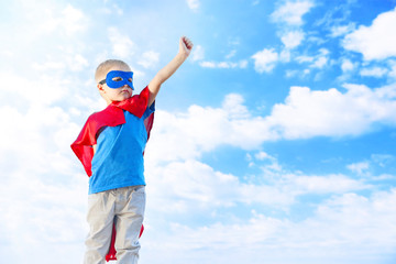 Superhero kid on blue sky background